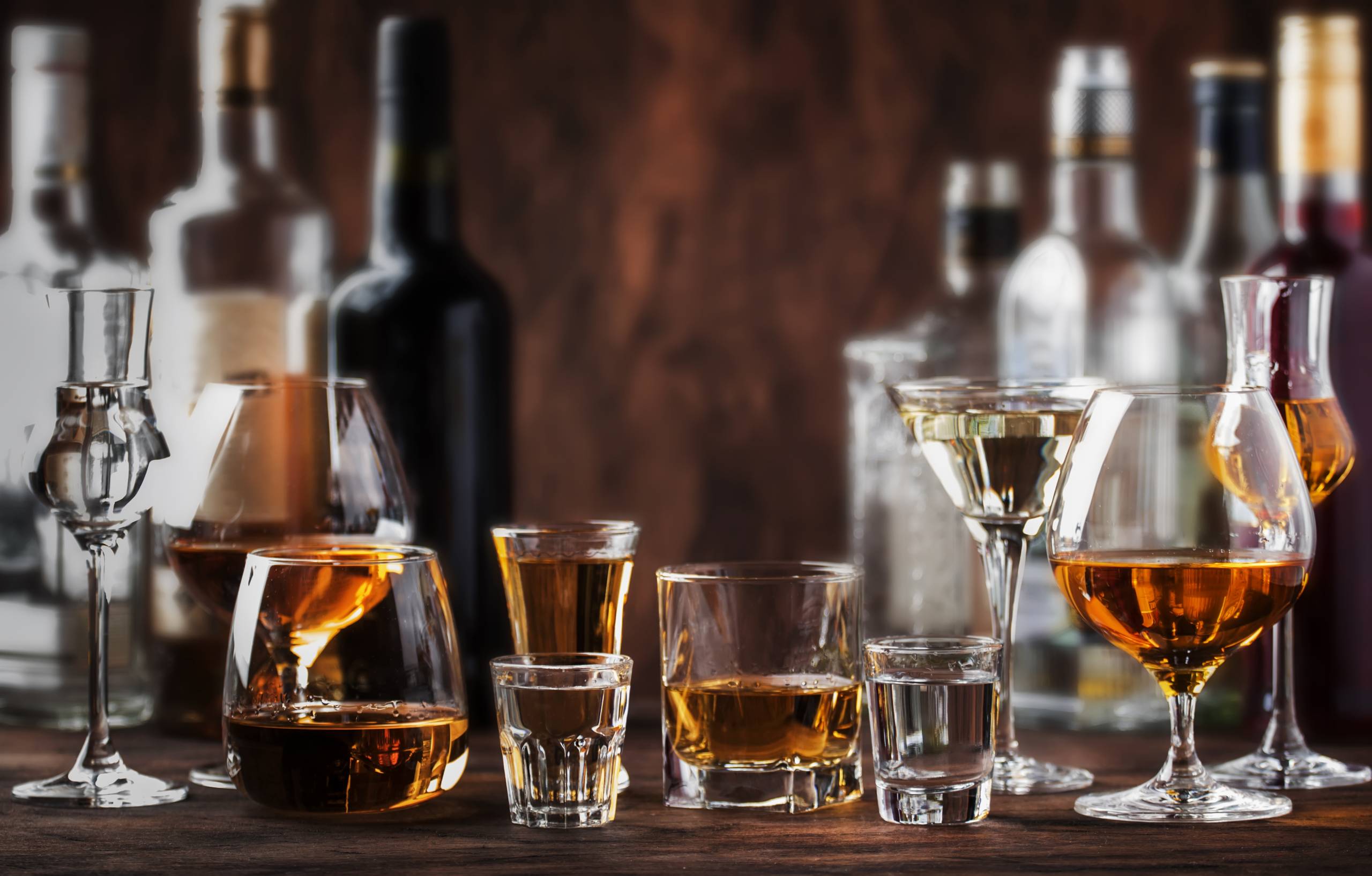 Strong Spirits Set. Hard alcoholic drinks in glasses in assortme Strong Spirits Set. Hard alcoholic drinks in glasses in assortment: vodka, cognac, tequila, brandy and whiskey, grappa, liqueur, vermouth, tincture, rum. Vintage bar counter background, selective focus